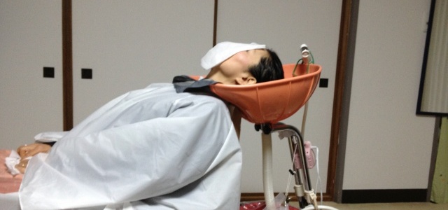 持ち運びできるシャンプー設備を使った施術の様子